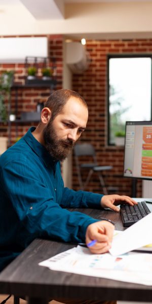 Businessman sitting at desk analyzing business paperwork working at management presentation planning company strategy in startup office. Entrepreneur looking at marketing documents